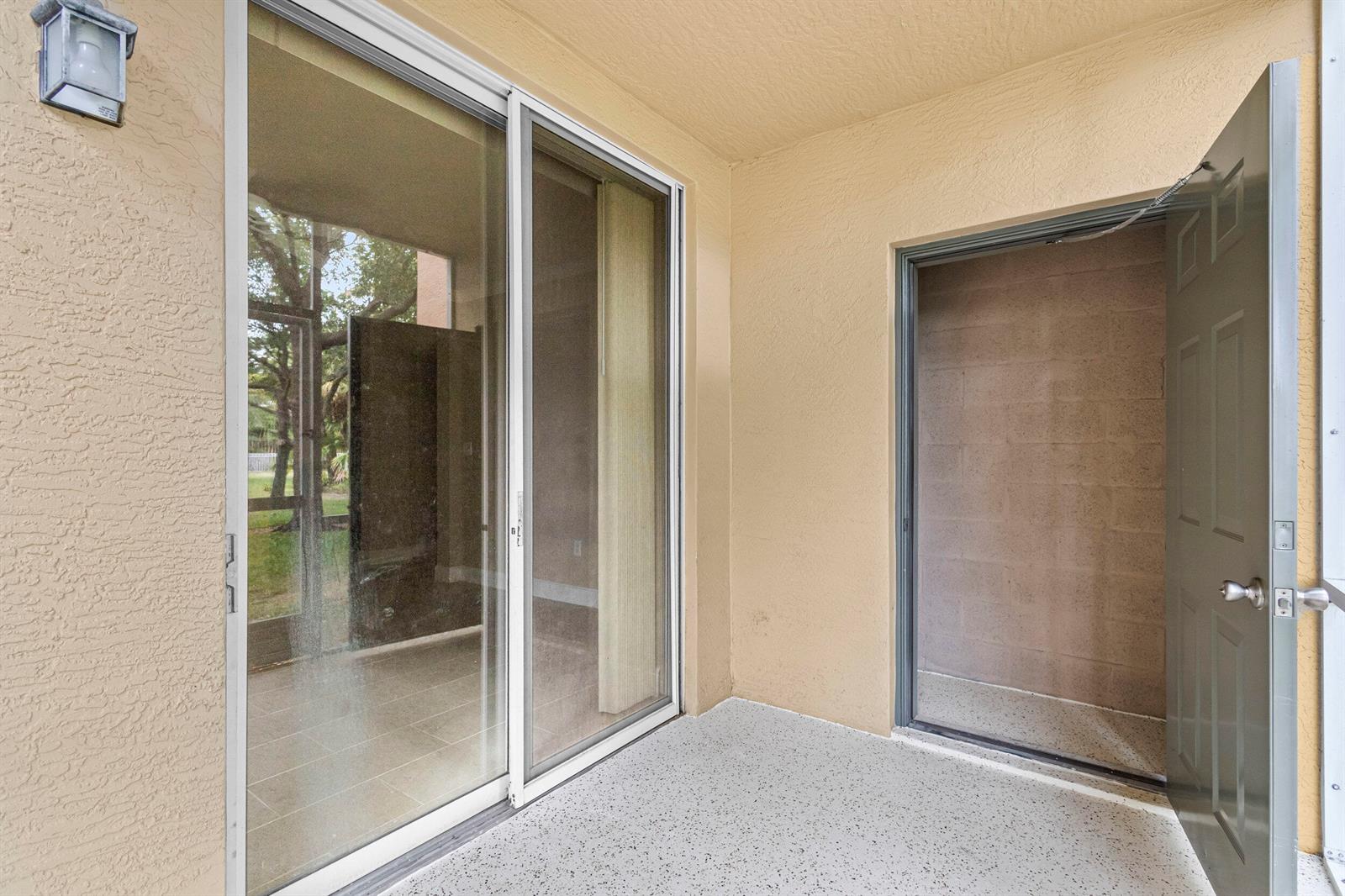 A covered patio features a sliding glass door, a storage closet, and light-colored flooring — 6450 Emerald Dunes Drive # 103, West Palm Beach FL 33411, WEST PALM BEACH, FL