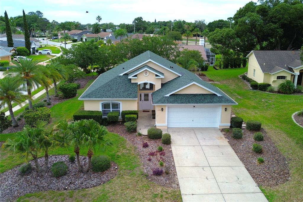 An aerial view of a single-story suburban house with a green roof and concrete driveway — 13748 MEADE COURT, HUDSON, FL