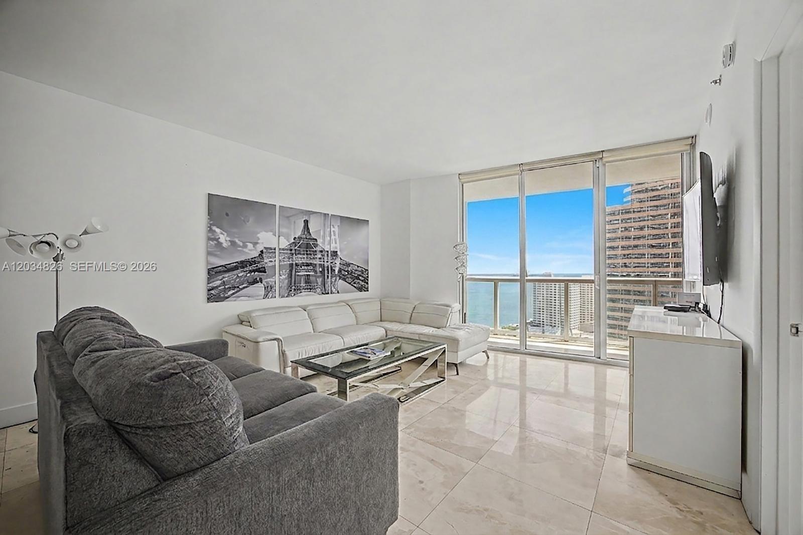 A living room features a grey sofa, white sectional, glass coffee table, and floor-to-ceiling windows — 485 Brickell Ave # 2209, Miami FL 33131, MIAMI, FL