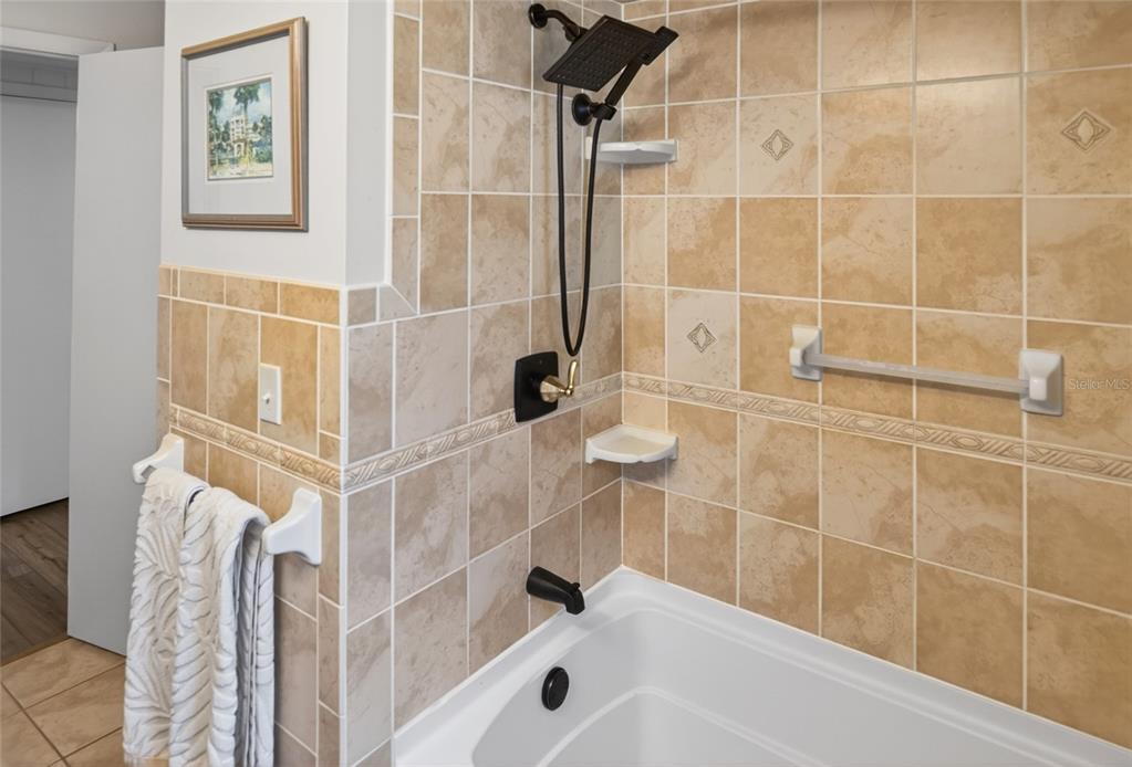 A tiled bathtub and shower combination features a dark bronze showerhead and faucet fixtures — 7588 S CRESCENT LOOP, FLORAL CITY, FL