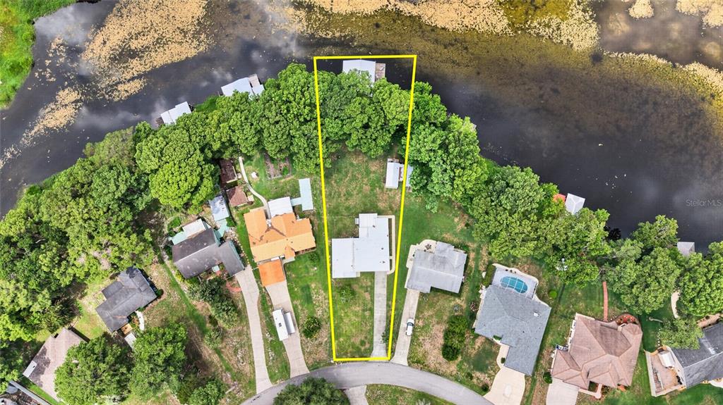 An aerial view shows a single-family home on a wedge-shaped lot bordering a lake — 7588 S CRESCENT LOOP, FLORAL CITY, FL