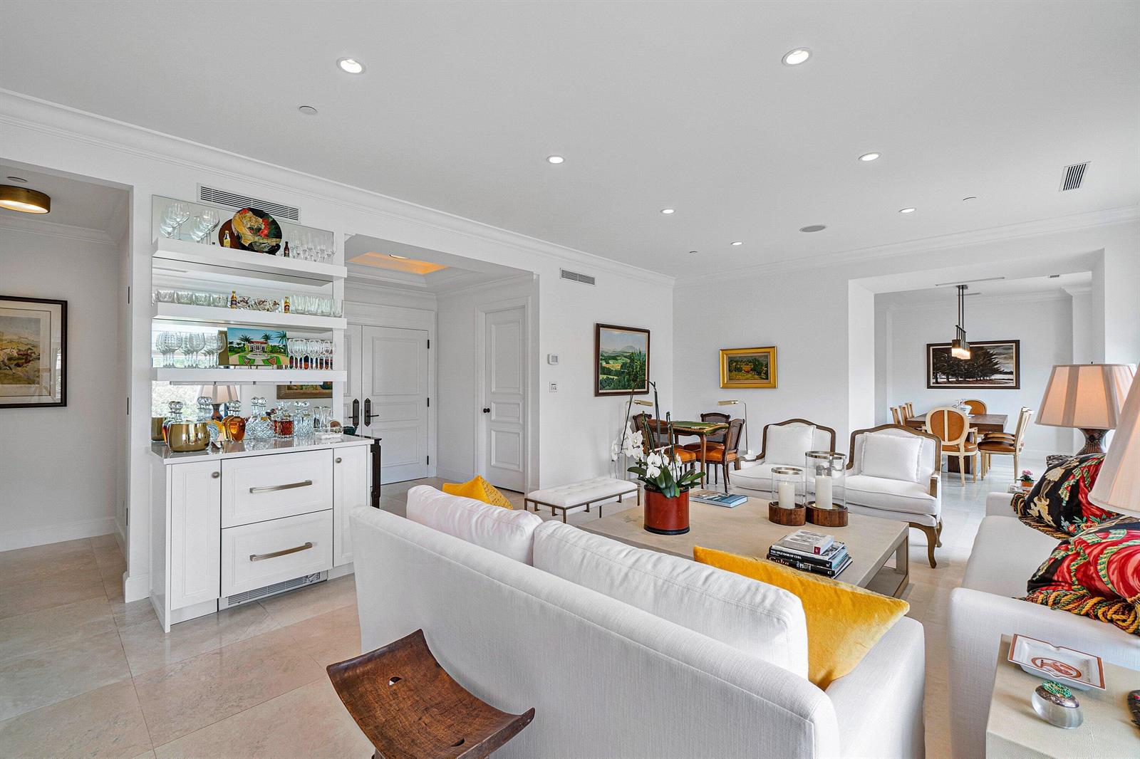 A bright, open-concept living room features a white bar area, neutral furniture, and dining space — 150 Bradley Place # 203, Palm Beach FL 33480, PALM BEACH, FL