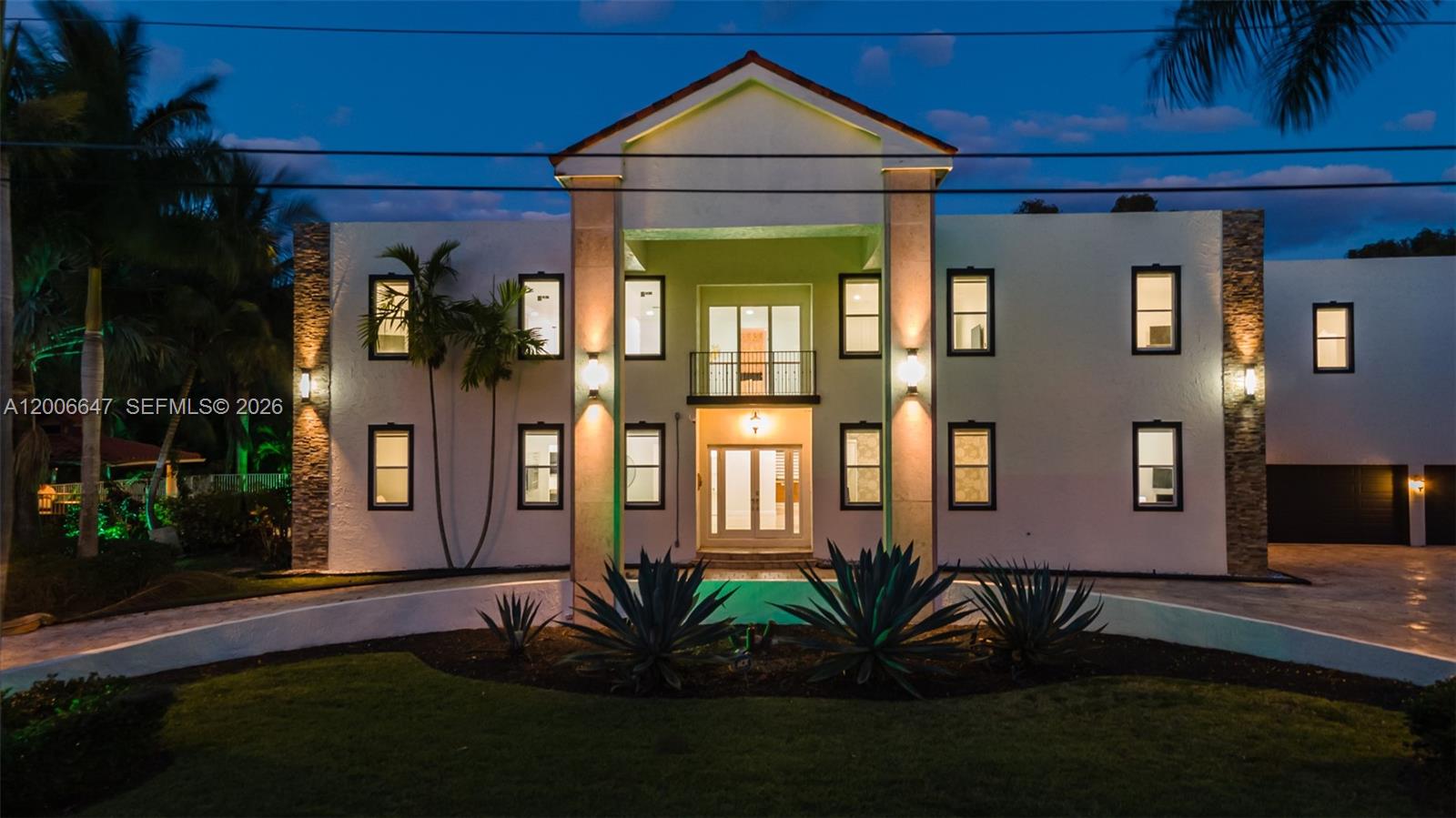 A two-story white house with a central balcony and stone accents at dusk — 1430 NW 114th Ave, Plantation FL 33323, PLANTATION, FL