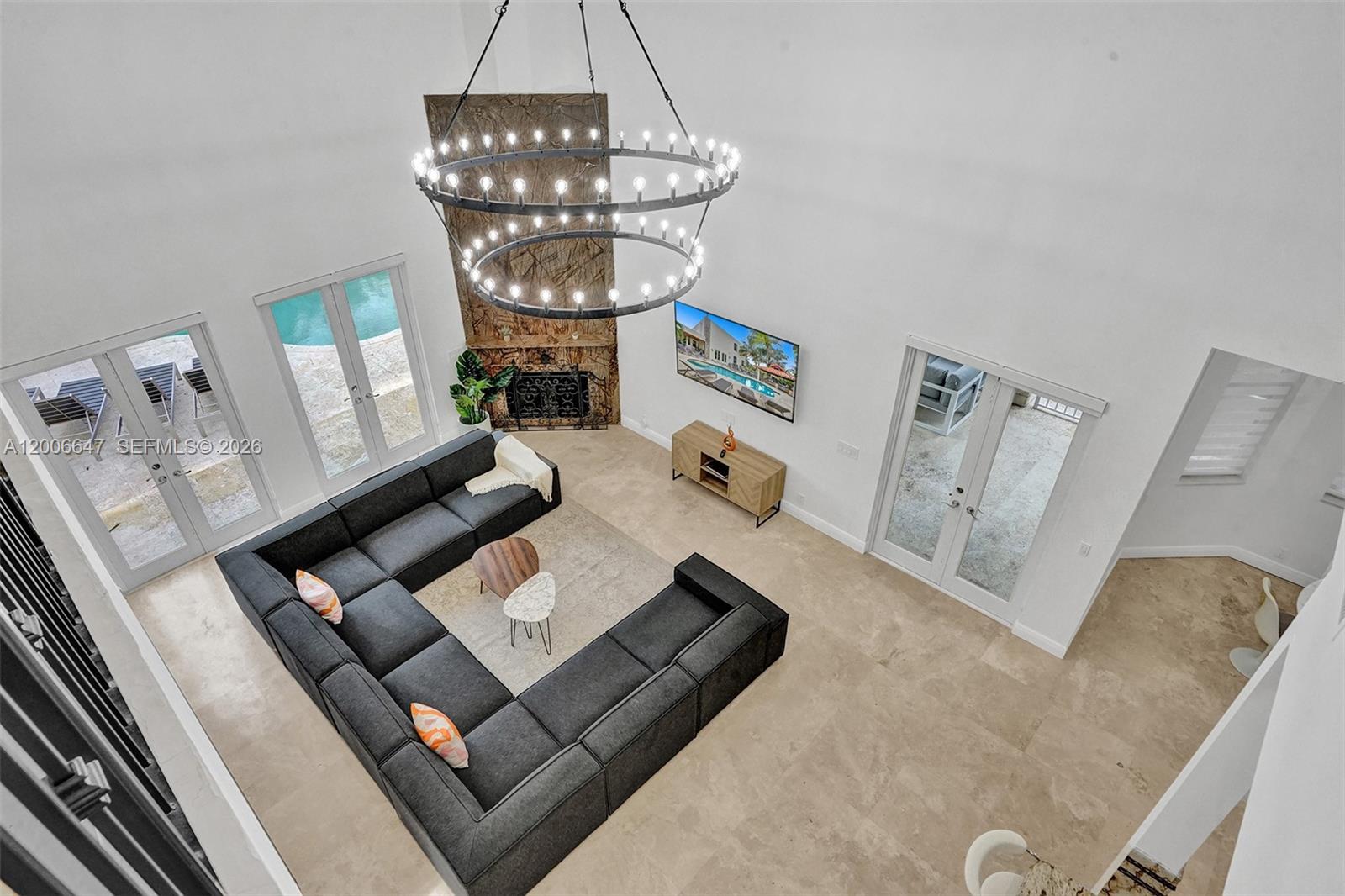 A high-ceiling living room features a large sectional sofa, a chandelier, and a fireplace — 1430 NW 114th Ave, Plantation FL 33323, PLANTATION, FL