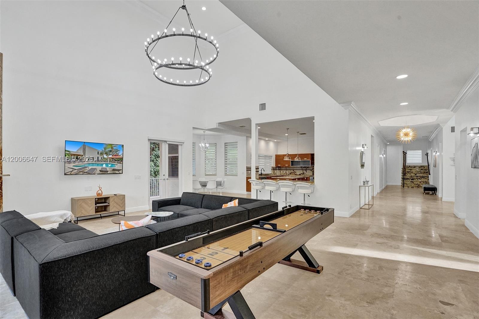 A spacious living room features a large sectional sofa, a shuffleboard table, and high ceilings — 1430 NW 114th Ave, Plantation FL 33323, PLANTATION, FL