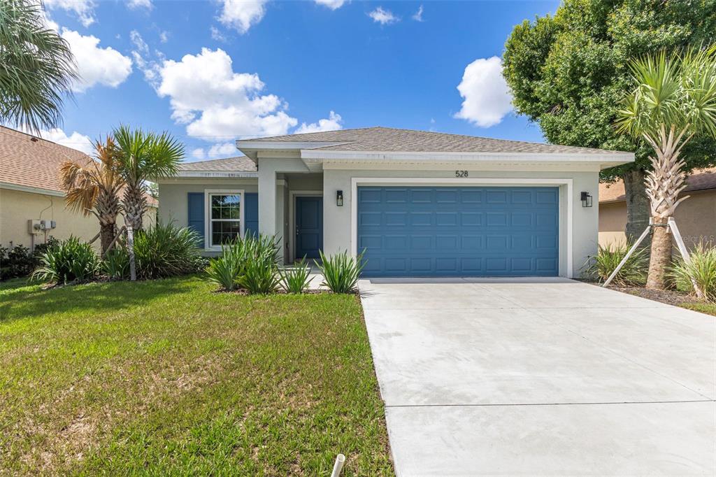A single-story house with a blue garage door, blue shutters, and palm trees in front — 528 ROSE APPLE CIRCLE, PORT CHARLOTTE, FL
