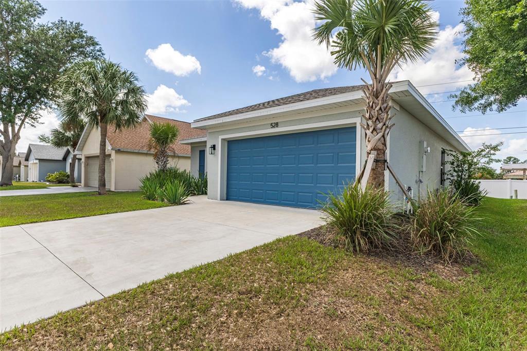 A single-story house with a blue garage door and a palm tree in the front yard — 528 ROSE APPLE CIRCLE, PORT CHARLOTTE, FL