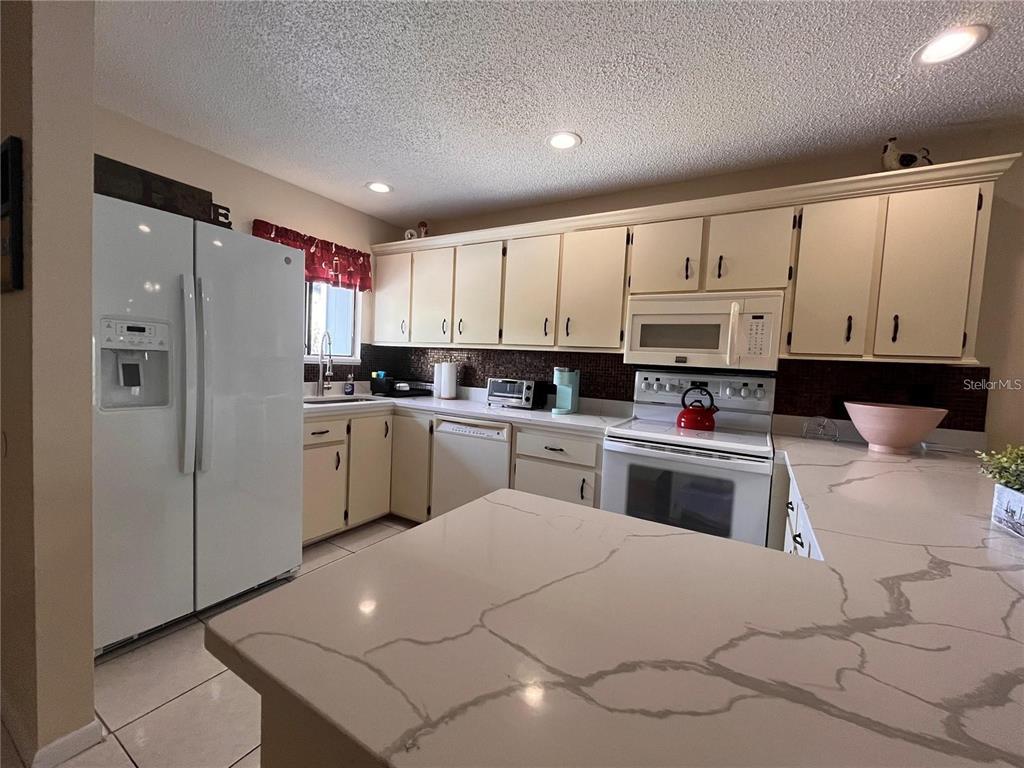 A kitchen features white cabinets, a white refrigerator, a white stove, and light-colored countertops — 6033 34TH STREET W UNIT 114, BRADENTON, FL
