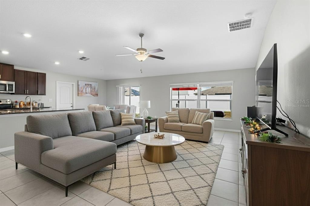A living room with a gray sectional, loveseat, round coffee table, and tile flooring — 889 CALICO SCALLOP STREET, RUSKIN, FL