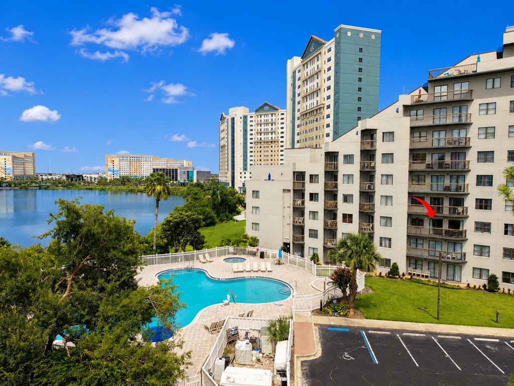 An exterior view of a multi-story resort building with a swimming pool and lake view — 6165 CARRIER DRIVE UNIT 2305, ORLANDO, FL