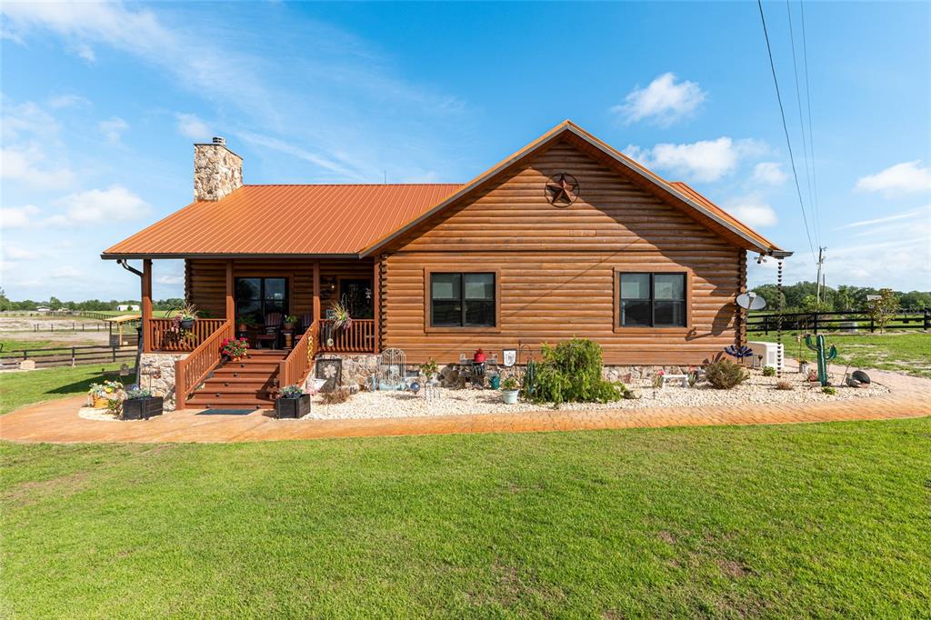 A single-story log cabin with a metal roof, stone chimney, and front porch — 2009 SW 20TH STREET, BELL, FL