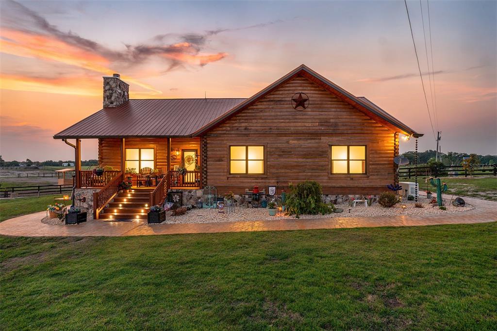 A rustic log cabin home with a metal roof and stone chimney at sunset — 2009 SW 20TH STREET, BELL, FL