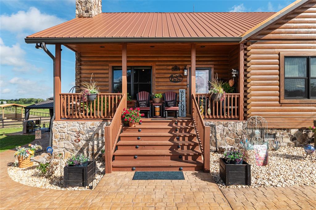 A log cabin features a covered front porch with wooden stairs and stone foundation accents — 2009 SW 20TH STREET, BELL, FL