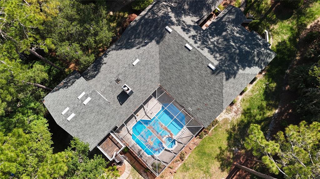 An aerial view of a house with a shingled roof and a screened-in swimming pool — 4616 NW 57TH DRIVE, GAINESVILLE, FL