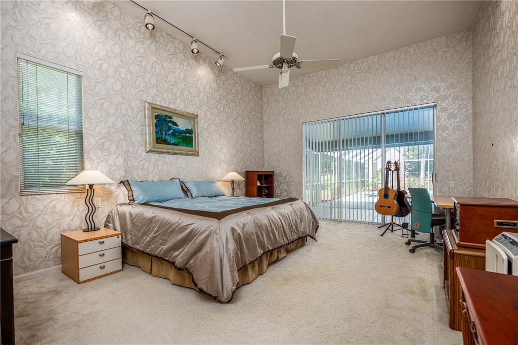 A bedroom with patterned wallpaper, a ceiling fan, a bed, and sliding glass doors — 4616 NW 57TH DRIVE, GAINESVILLE, FL
