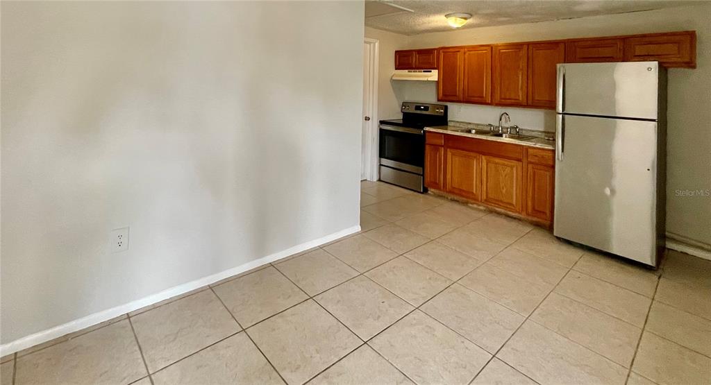 A kitchen with light tile floors, wood cabinets, and stainless steel appliances — 9803 N 11TH STREET UNIT B, TAMPA, FL