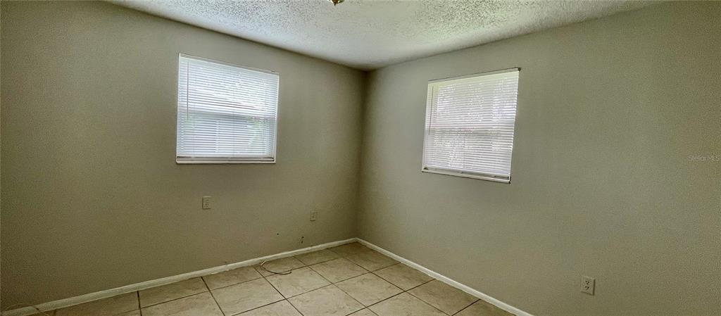 An empty room with light gray walls, tiled floors, and two windows with white blinds — 9803 N 11TH STREET UNIT B, TAMPA, FL