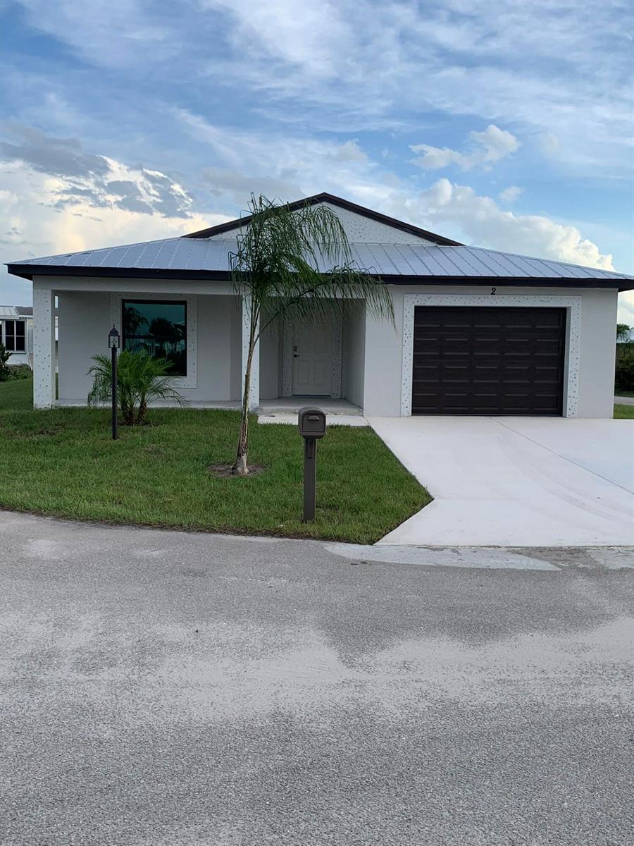 A single-story house with a metal roof, white stucco exterior, and a dark garage door — 43 La Villa Way, Fort Pierce FL 34951, FORT PIERCE, FL