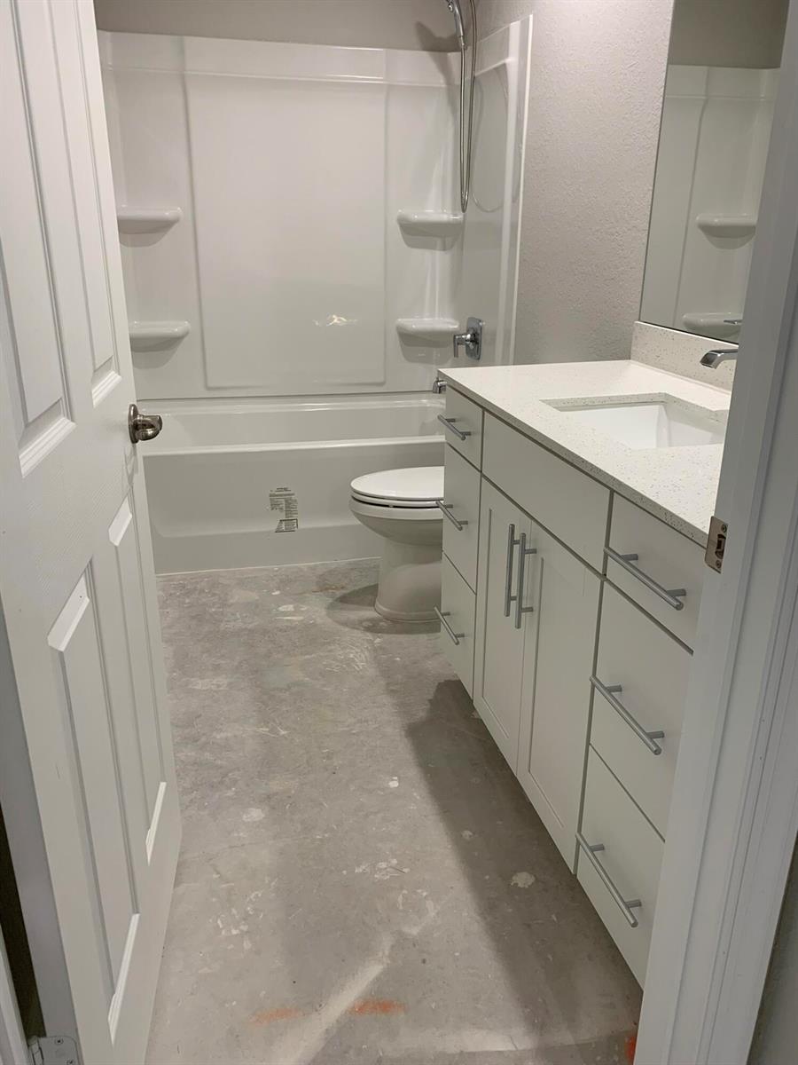 A bathroom with a white vanity, a tub-shower combination, and an unfinished concrete floor — 43 La Villa Way, Fort Pierce FL 34951, FORT PIERCE, FL