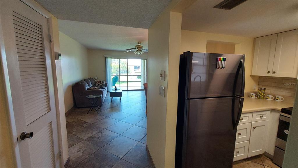 A view from a kitchen looking into a living room with tile floors and sliding doors — 5154 TURQUOISE LANE UNIT 201, NEW PORT RICHEY, FL