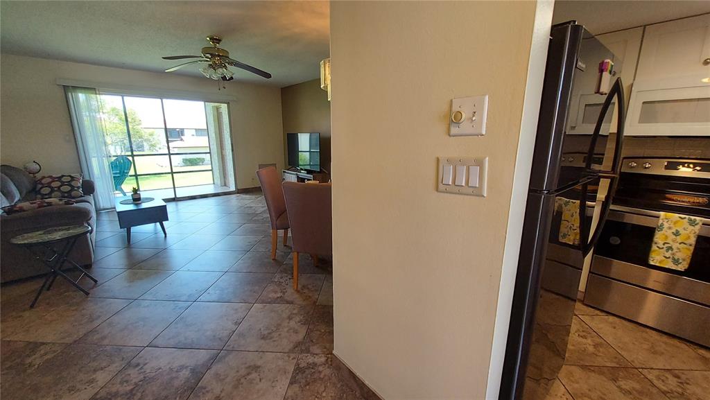 A view from a kitchen looking into a living room with tile floors and sliding doors — 5154 TURQUOISE LANE UNIT 201, NEW PORT RICHEY, FL