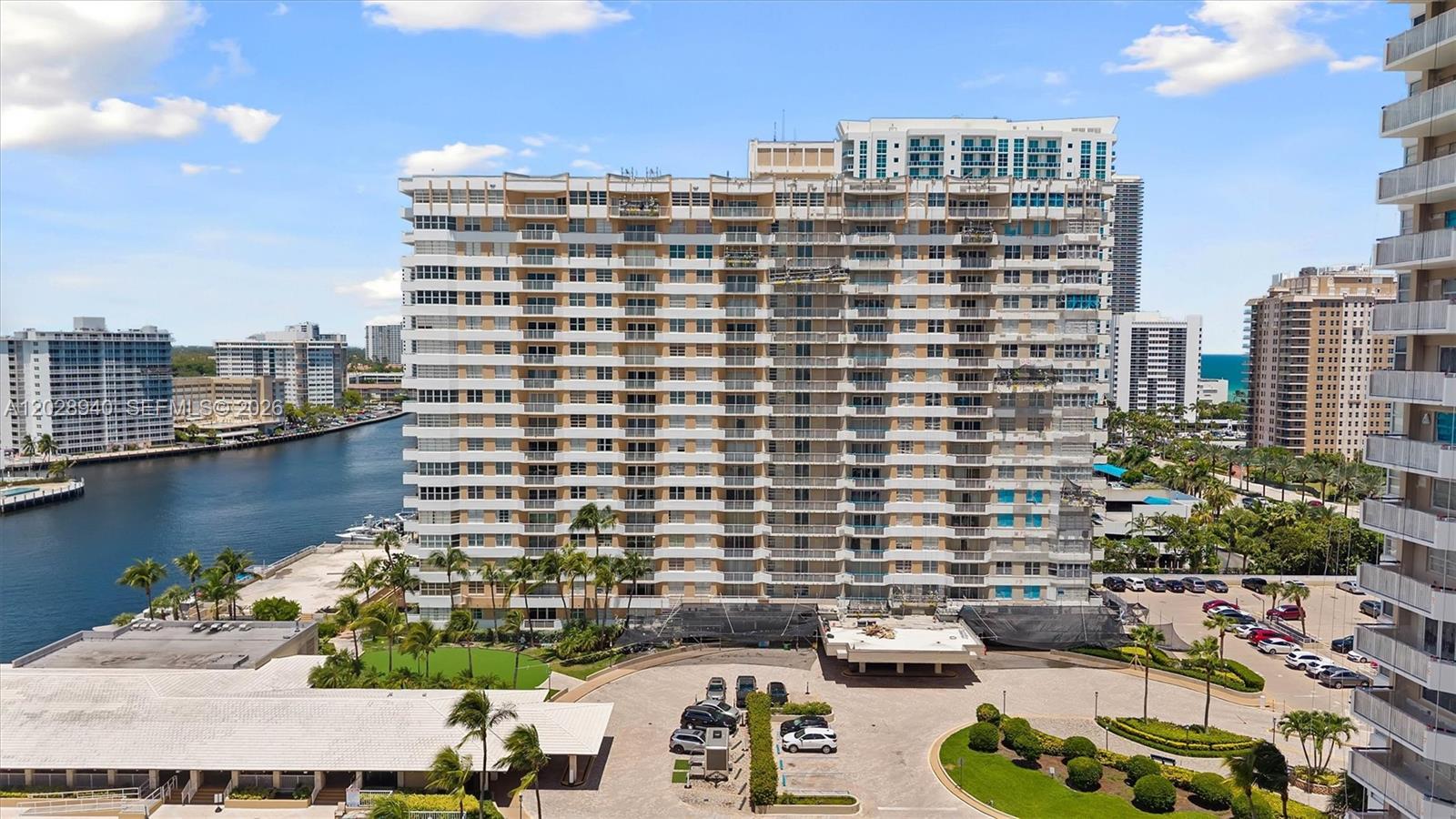 An exterior view of a tall residential apartment building with balconies and a parking lot — 1965 S Ocean Dr # 3L, Hallandale Beach FL 33009, HALLANDALE BEACH, FL