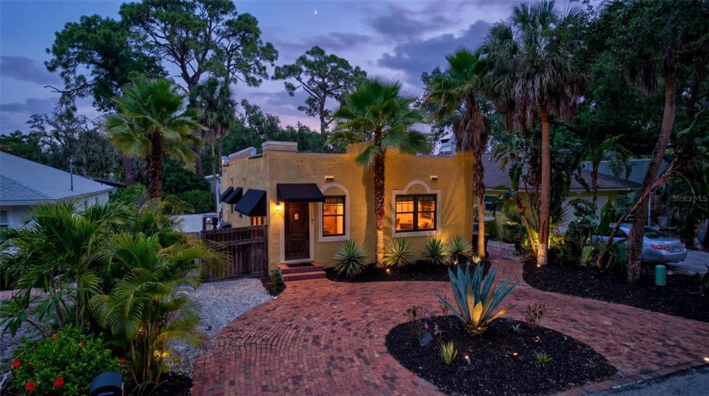A yellow stucco house with a brick driveway and palm trees at twilight — 2437 FLOYD STREET, SARASOTA, FL