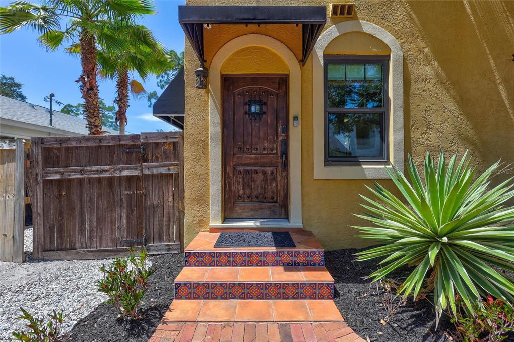 A wooden front door with a metal awning sits above tiled steps and a walkway — 2437 FLOYD STREET, SARASOTA, FL