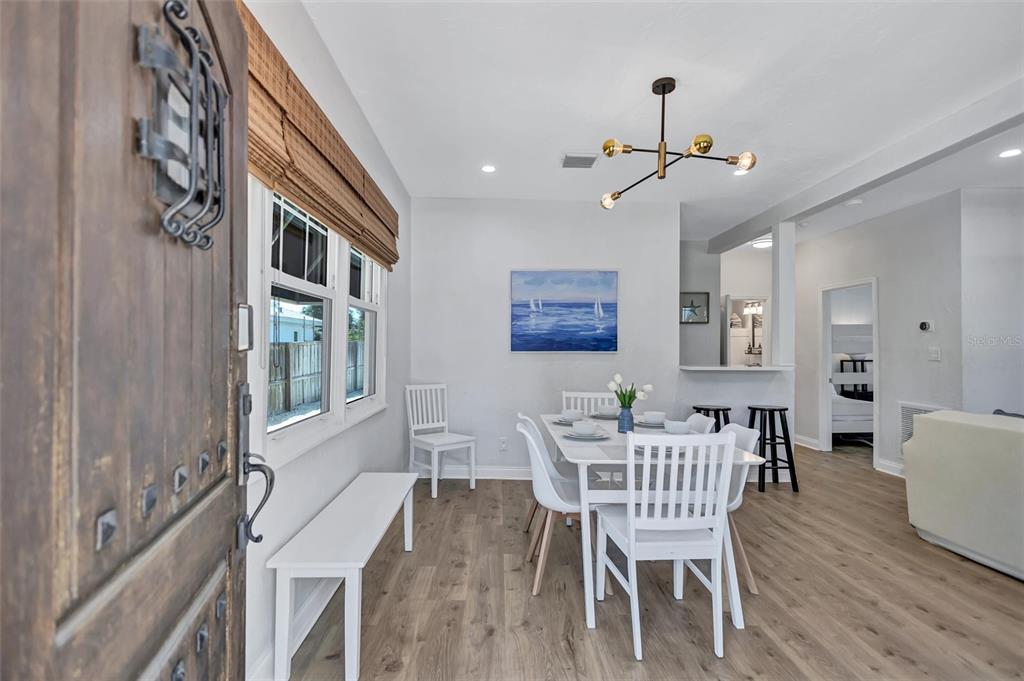 A dining area features a white table and chairs, wood-look flooring, and a modern chandelier — 2437 FLOYD STREET, SARASOTA, FL