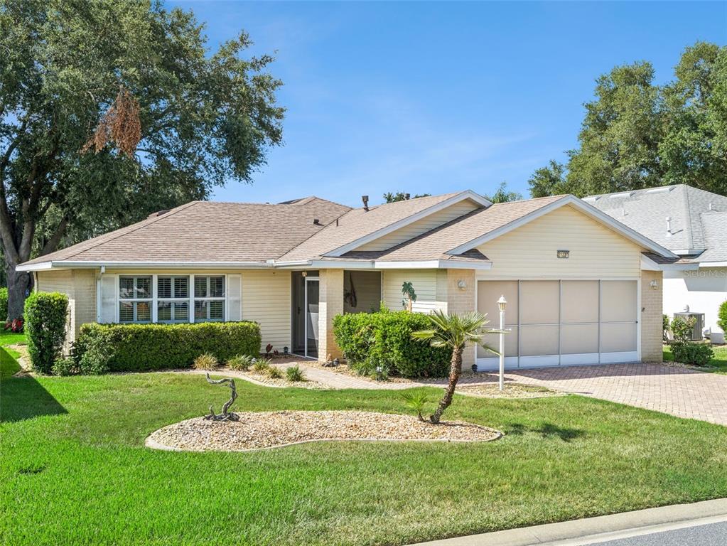 A single-story house with light siding, a brick facade, and a paved driveway — 21230 ROYAL ST GEORGES LANE, LEESBURG, FL