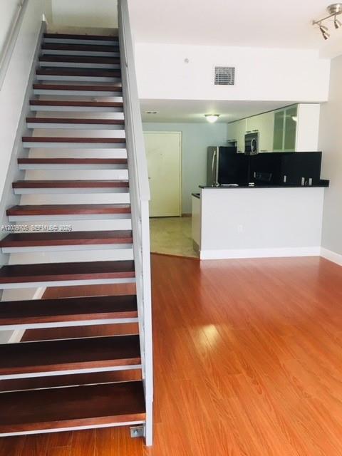 A staircase with dark wood treads stands in a room with light wood flooring — 3339 Virginia St # 105, Miami FL 33133, MIAMI, FL