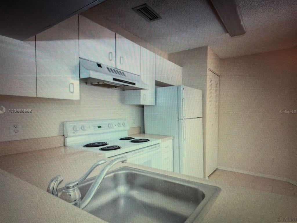 A kitchen features white cabinets, a white stove, a refrigerator, and a stainless steel sink — 1040 CORAL SPRINGS CLUB UNIT 1040, CORAL SPRINGS, FL