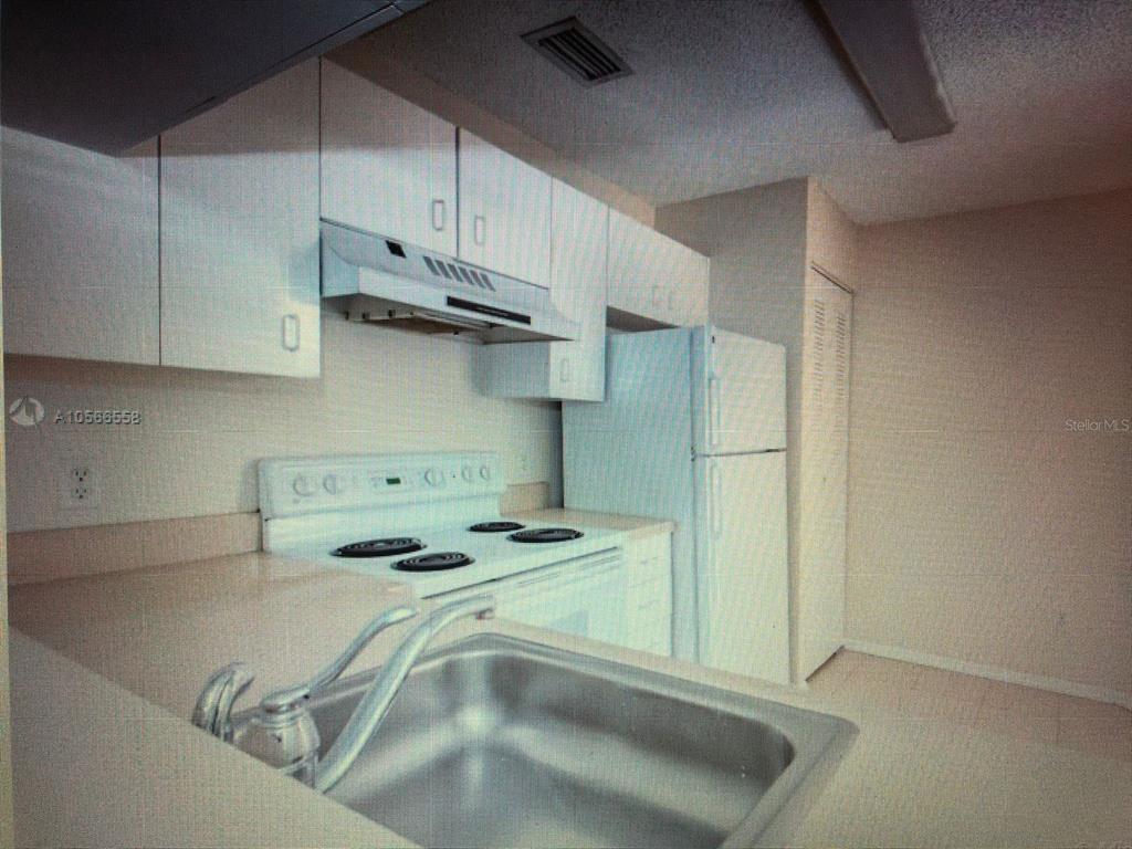 A kitchen features white cabinets, a white stove, a refrigerator, and a stainless steel sink — 1040 CORAL SPRINGS CLUB UNIT 1040, CORAL SPRINGS, FL