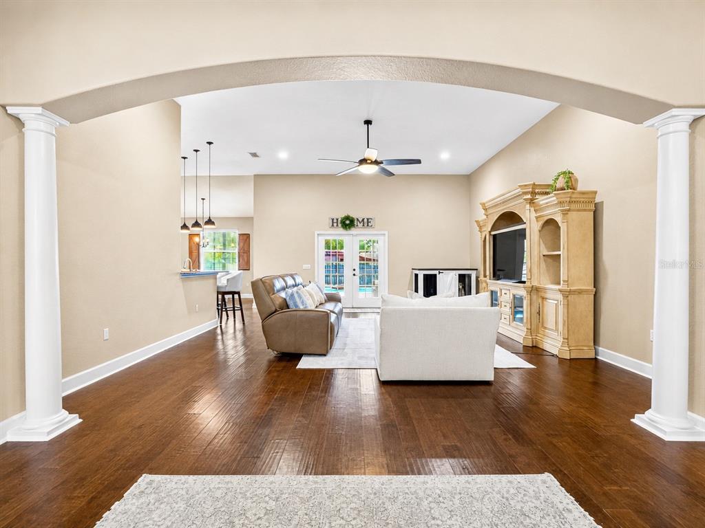 A living room with hardwood floors, a large entertainment center, and a view of the pool — 1939 GRIFFIN TRAIL, BARTOW, FL