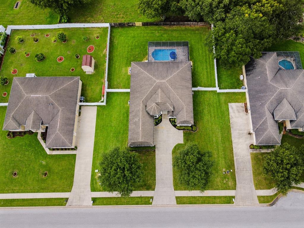 An aerial view shows three suburban houses with driveways, green lawns, and backyard swimming pools — 1939 GRIFFIN TRAIL, BARTOW, FL