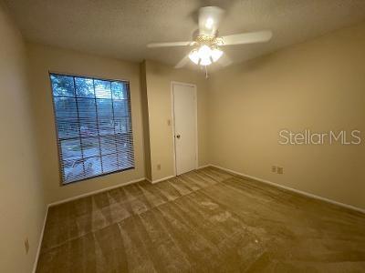 A carpeted bedroom features a ceiling fan, a window with blinds, and a closed door — 8653 MALLARD RESERVE DRIVE UNIT 201, TAMPA, FL