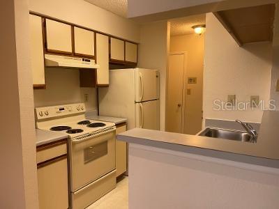 A kitchen features off-white cabinets, a white electric range, a refrigerator, and a breakfast bar — 8653 MALLARD RESERVE DRIVE UNIT 201, TAMPA, FL