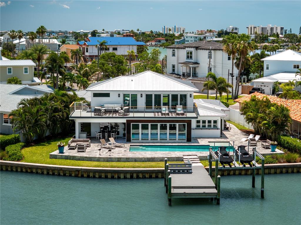 A modern two-story house features a swimming pool, patio, and large folding glass doors — 16117 4TH STREET E, REDINGTON BEACH, FL