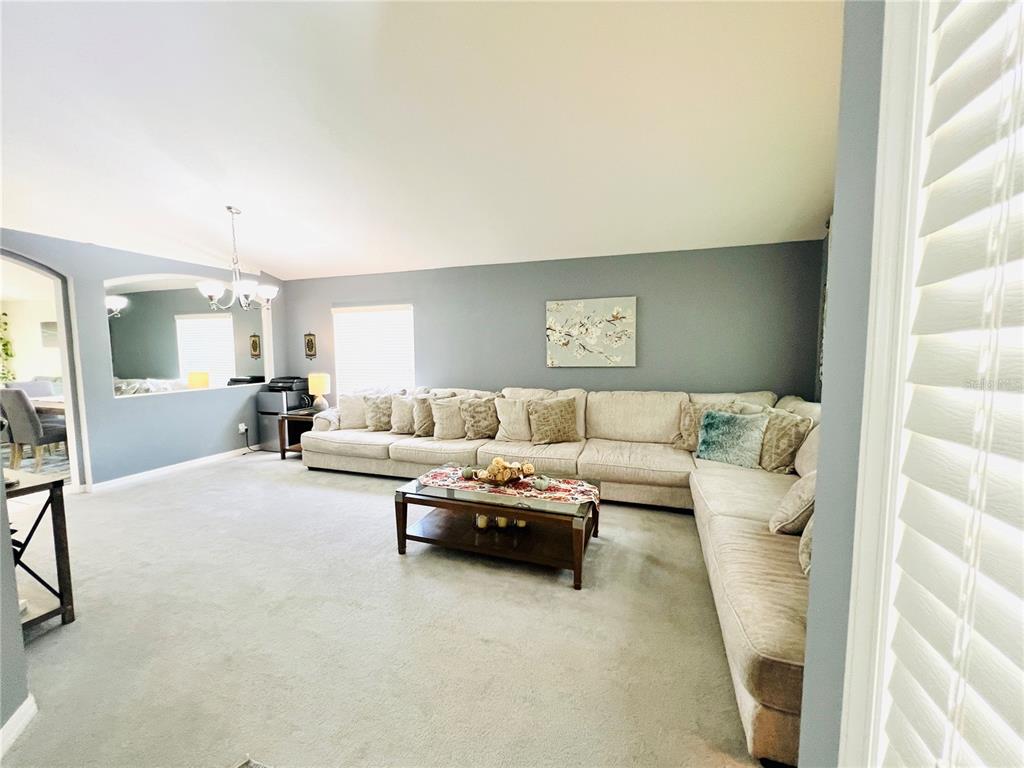 A spacious living room features a large beige sectional sofa, a coffee table, and blue walls — 2859 STAGS LEAP DRIVE, ORANGE CITY, FL