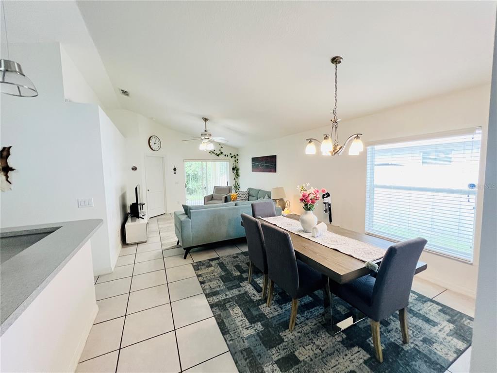 An open-concept dining and living area features tile flooring, a dining set, and sectional sofa — 2859 STAGS LEAP DRIVE, ORANGE CITY, FL
