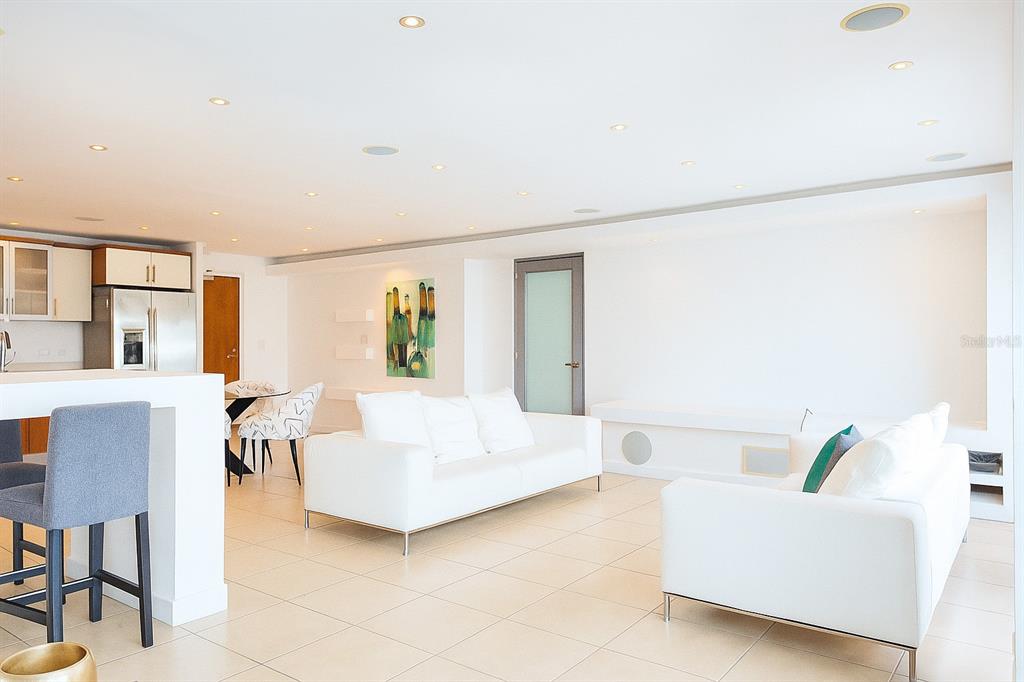 A bright, open-concept living room features white sofas, tile flooring, and recessed ceiling lighting — 103 AVENIDA DE DIEGO UNIT N/A, SAN JUAN, PR