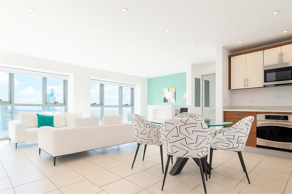 A bright, open-concept living and dining area features white tile floors, modern furniture, and windows — 103 AVENIDA DE DIEGO UNIT N/A, SAN JUAN, PR