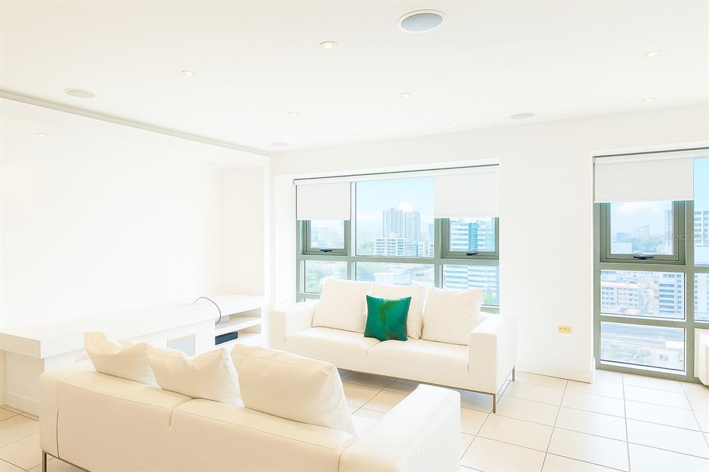 A bright living room features white sofas, tiled floors, and large windows with city views — 103 AVENIDA DE DIEGO UNIT N/A, SAN JUAN, PR