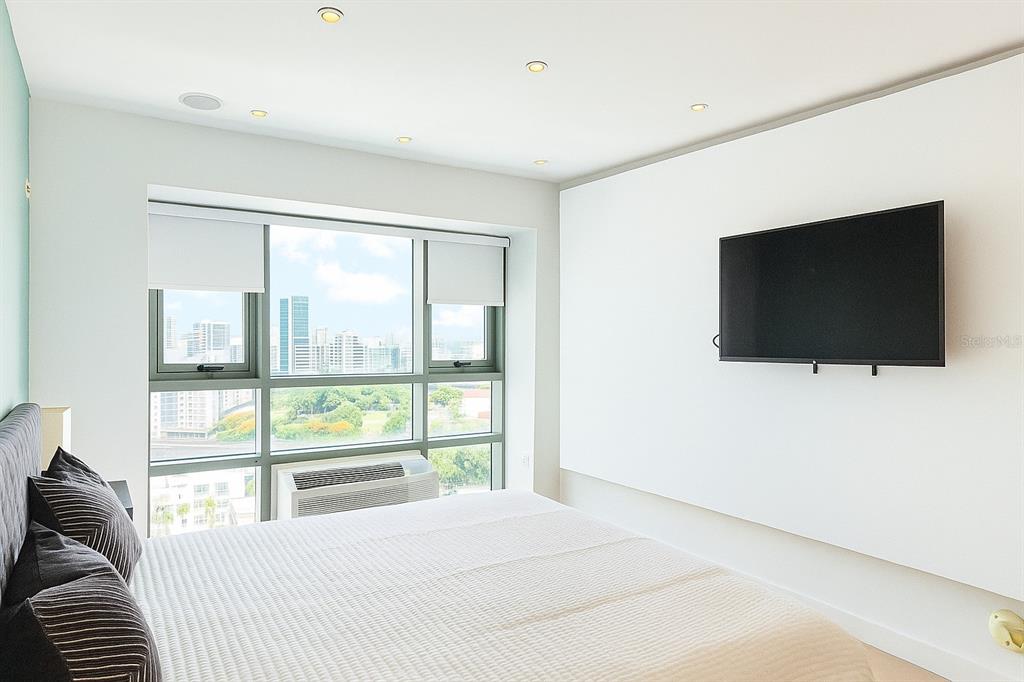 A bedroom features a bed, a wall-mounted television, and large windows overlooking a city skyline — 103 AVENIDA DE DIEGO UNIT N/A, SAN JUAN, PR