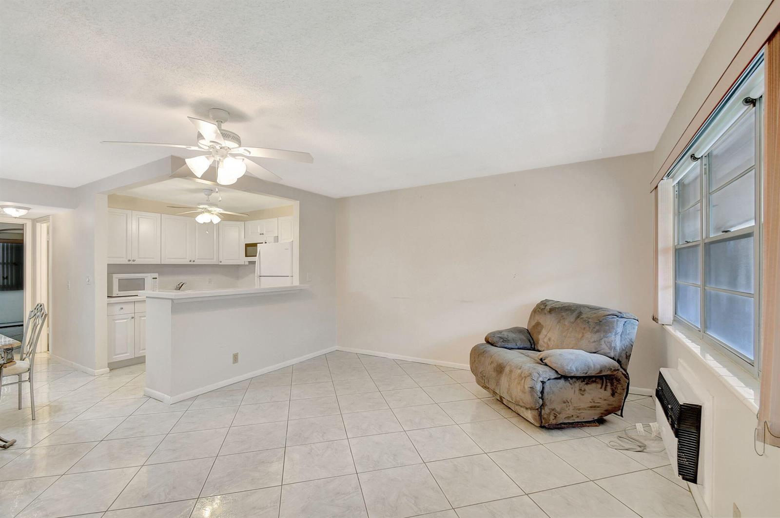 A living room with light tile flooring, a ceiling fan, and a recliner near a window — 70 Camden C, West Palm Beach FL 33417, WEST PALM BEACH, FL