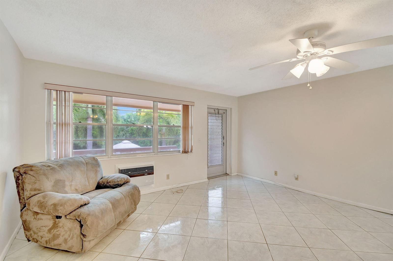A living room features light-colored tile flooring, a ceiling fan, a recliner, and a window — 70 Camden C, West Palm Beach FL 33417, WEST PALM BEACH, FL