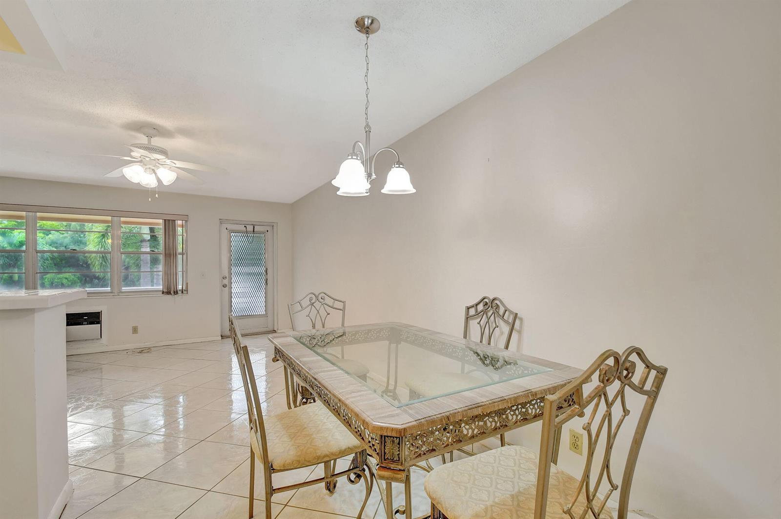 A dining area features a glass-topped table, metal chairs, tile flooring, and a pendant light — 70 Camden C, West Palm Beach FL 33417, WEST PALM BEACH, FL