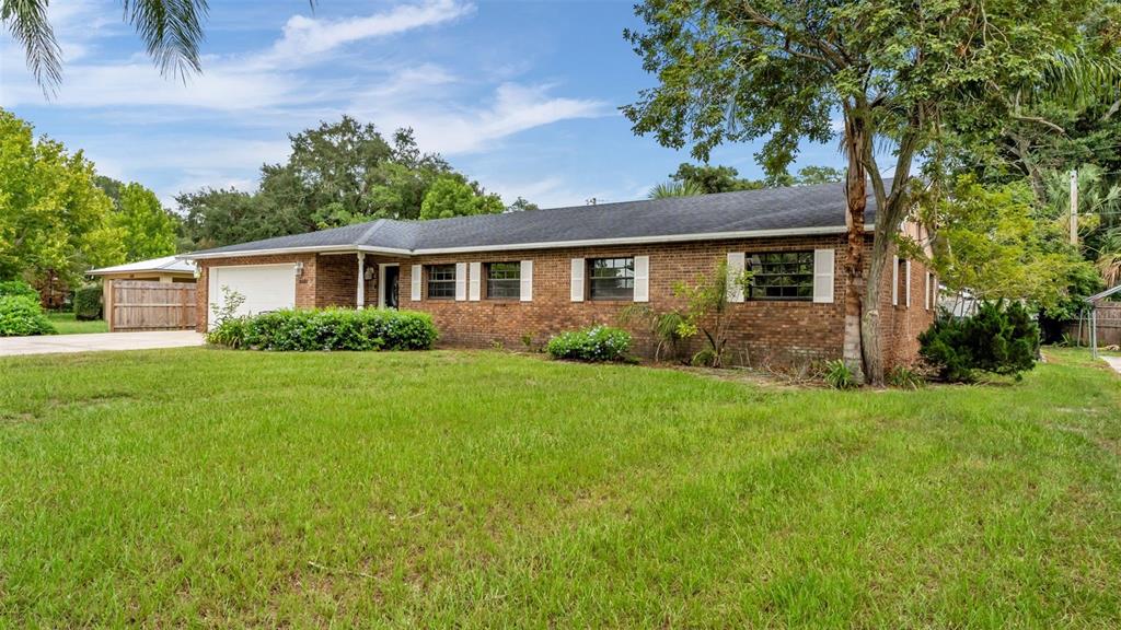 A single-story brick house with a garage and a large front lawn under a blue sky — 4020 GLEN GARRY ROAD W, LAKELAND, FL