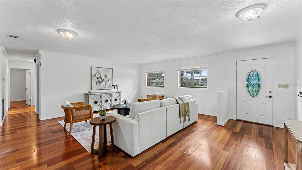 A living room with white walls, hardwood floors, a white sofa, and a front door — 4020 GLEN GARRY ROAD W, LAKELAND, FL
