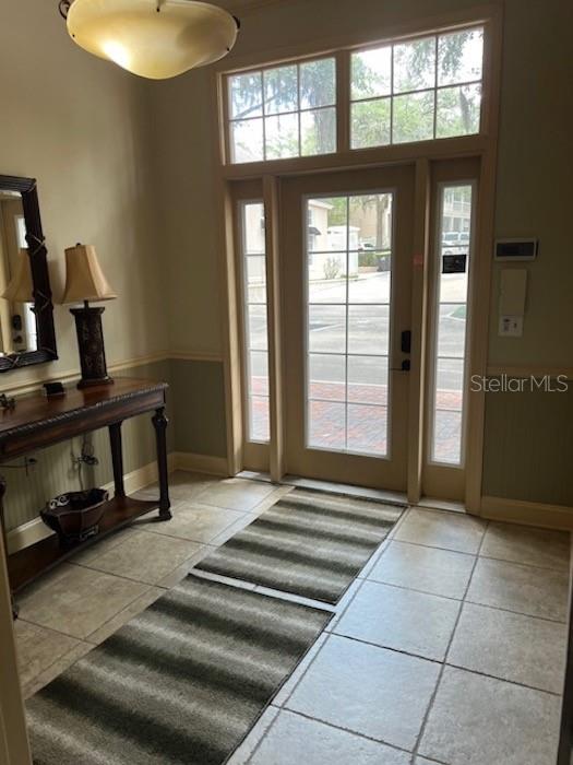 An entryway features a console table, a lamp, a tiled floor, and a glass-paneled front door — 5216 SW 91ST TERRACE UNIT A106, GAINESVILLE, FL